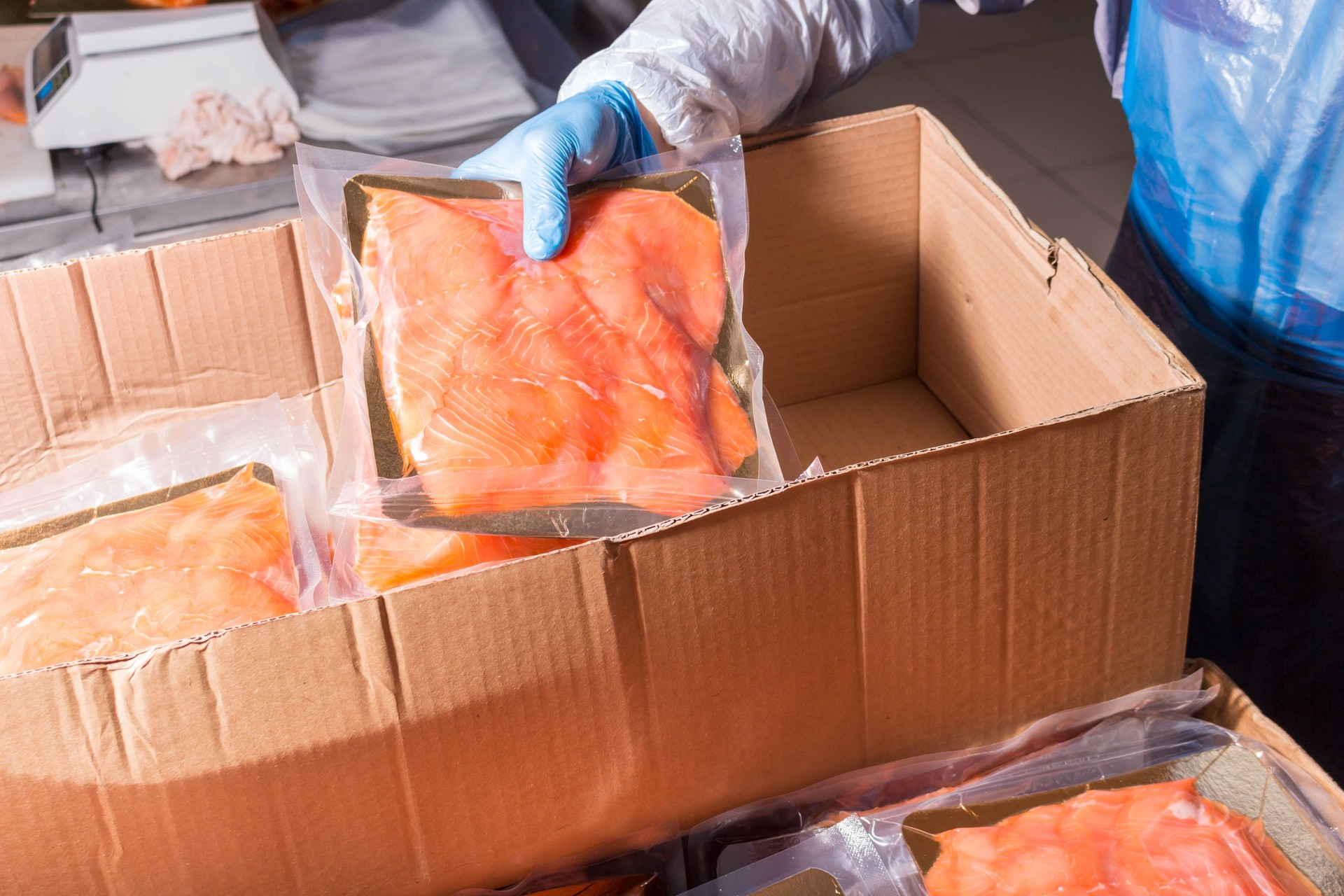 Fish production. The worker puts the finished product into a box for transportation.